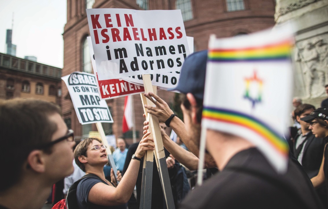 Ein Foto der Demonstration vor der Paulskirche. Zu sehen ist ein Transparent mit der Aufschrift »Kein Israelhass im Namen Adornos«